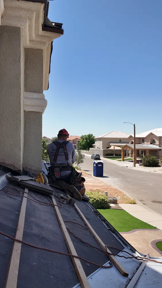 Roofing crew working a sloped section above a residential street